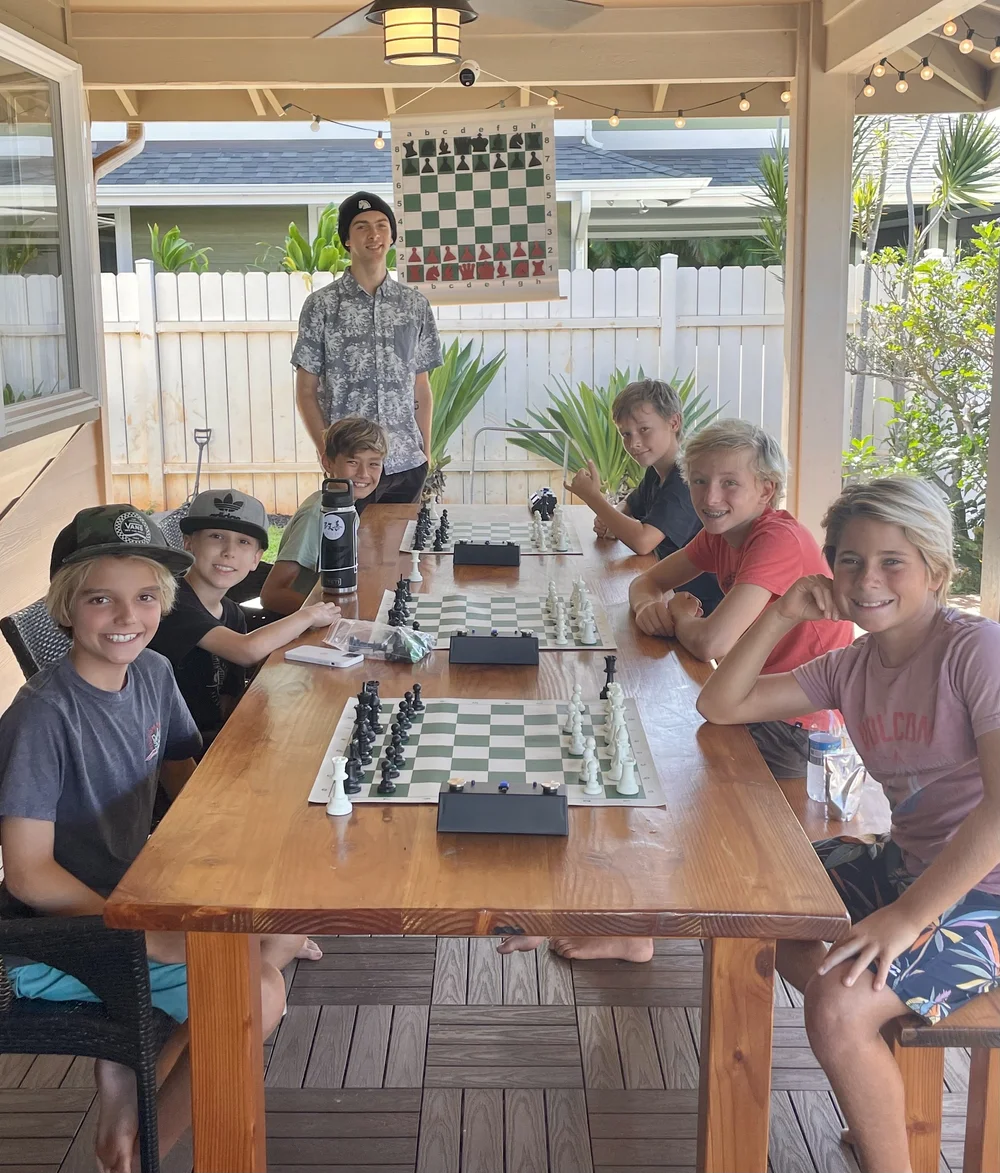 Coach Andre with a group of students around a chess table